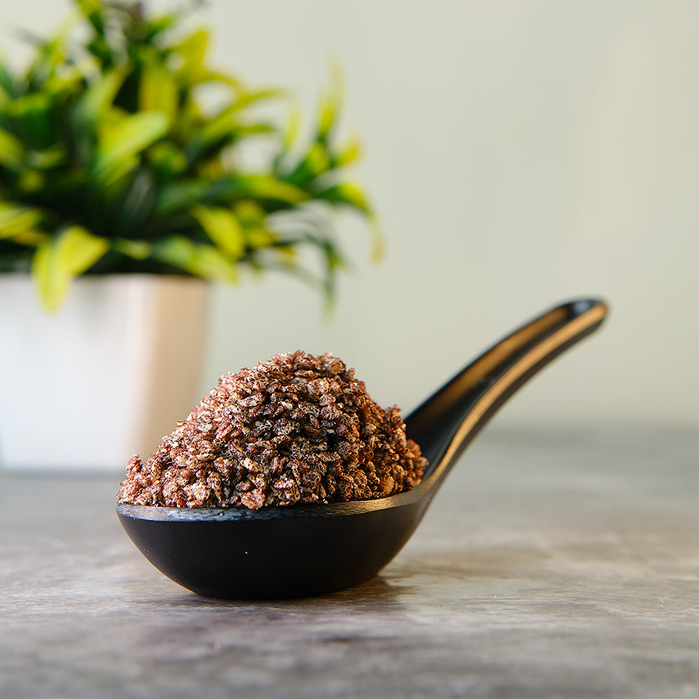 A spoonful of puffed ragi (a type of millet) against a backdrop featuring a plant pot.